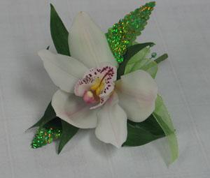 A single white cymbidium orchid with iridescent green leaves. This is a stunning and modern approach to the corsage or boutonniere.