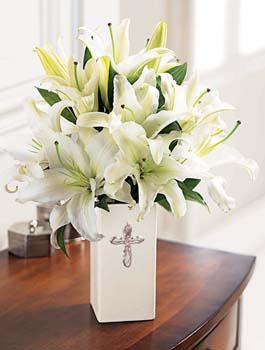 This striking display of pure white lilies will send your heartfelt expressions when words just aren't enough. Arranged in a white ceramic vase and enhanced by a silvertone cross, this arrangement is perfect for First Communion celebrations, confirmations, Sympathy, Weddings, or a religiousl Anniversary.