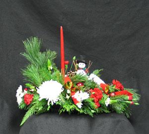 The cutest Frosty the Snow ever!! The Pine, Cedar, Douglas Fir, cones, velvet bows, glass balls , red candle, white Commercial mums, red carnations and flat mums complete this festive centrepiece.Delivered fresh.