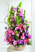 Superb Stargazer lilies with lavender roses, pink variegated carnations, and liatris with Bells of Ireland are arranged in a bamboo dish garden..