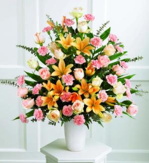 This splendid and formal  arrangement includes 18 peach roses, 24 pink carnations and peach Asiatic lilies with baby blue eucalyptus. All are arranged in a simple  white container.