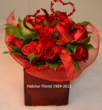 12 red roses arranged in a contemporary style. The red glass cube accentuates the vibrant red of the Freedom roses. Red hearts and fabric wrap complete the design. These are Eco from Sierra. We deliver from our flower shop for you. Florist fresh flowers guaranteed.