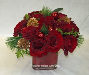 A group of 12 red Freedom roses in a glass cube with pine, fir, gold cones, red glass balls will brighten any office or home setting. The red roses are so rich against the pine and gold cones.