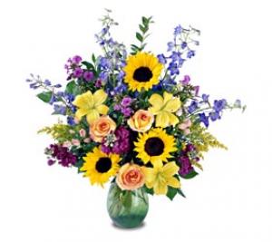 An impressive presentation of flowers. A rainbow of colours in a glass vase. This arrangement is the perfect gift for any occasion with its Roses, Lilies, Sunflowers, and more.