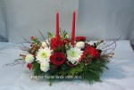 Two red tapers to light your Christmas family dinner, or your best friend's party table. Seasonal pine, fir, red blueberry branches, cones, roses, ribbons, and mixd mums.