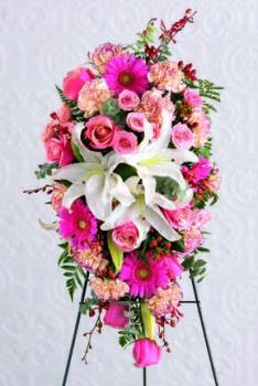 Beautiful standing spray of three white Oriental lilies surrounded by pink Gerbera daisies, pink roses, variegated pink carnations and orchids.We deliver to all Toronto and area funeral homes.