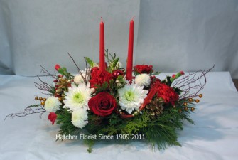 Two red tapers to light your Christmas family dinner, or your best friend's party table. Seasonal pine, fir, red blueberry branches, cones, roses, ribbons, and mixd mums.