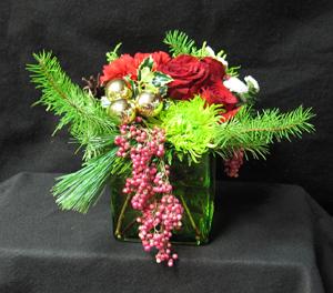 Winter forest in your home, enjoy this small arrangement for yourself, or as a gift. Artificial, Pepperberry, Fir, Pine, cones, red Freedom roses, gold balls, Holiday ribbon green Rivert mum, and white Chrysanthemums, and hardy red Carnations.