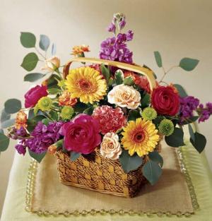 This brightly colored bouquet arrives in a basket and will fill any room with color. Arrangement includes peach spray roses, hot pink ranunculus, orange mini gerbera daisies, purple Stock and more.