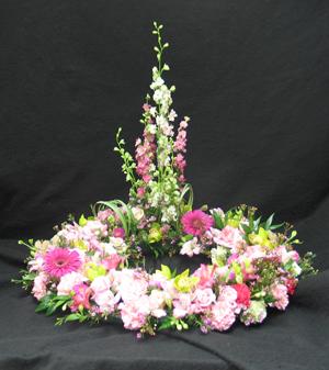 Wreath style tribute to insert a picture of a loved one. Made with cymbidium orchids, roses, larkspur, wax flower and more. Hatcher original. We deliver flowers made by our floral designers daily.