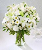 The innocence of a child is reflected in this arrangement of pure white flowers. All white carnations, alstroemeria, daisy and button poms and lilies are lovingly designed in a clear glass vase.