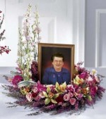 Small roses, hot pink mini Gerbera daisies, pink larkspur and heather are combined in this beautiful wreath. This design of pink blooms is intended to embrace a photo of your Loved one during a memorial service.