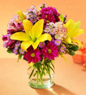 Celebrate Happy Times - past, present and future. Yellow Asiatic lilies and purple daisy poms are sprinkled with mini carnations and lavender monte casino and arranged in a clear glass vase. It's the perfect birthday gift!